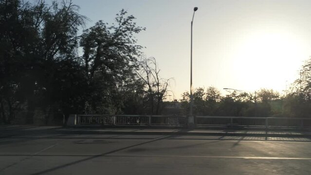 urban cityscape trees, street, overpass, pan left during sunset