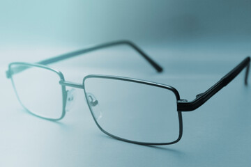 Glasses in a black frame on a blue background with copy space. World Day of Sight. Blurred...