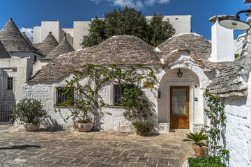 Fototapeta na wymiar narrow cobblestone streets and round stone trulli houses in Arbelobello. Stone pointed roofs and brick stone whitewashed houses on a sunny day