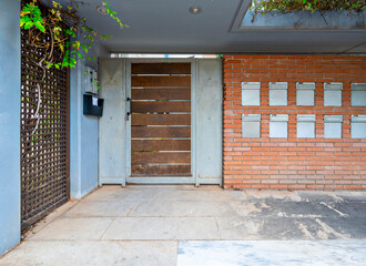 A contemporary residential apartment building main entrance with a wooden door and fourteen mail boxes. Athens, Greece.