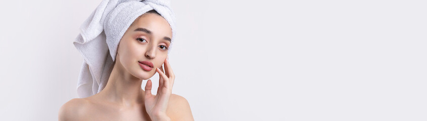 Beautiful girl with thick eyebrows and perfect skin at white background, towel on head, beauty photo.