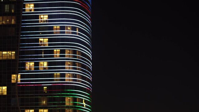 Close-up. Office building with glowing windows against the background of the night sky. Screensaver for a real estate site. Business center in Uzbekistan.
