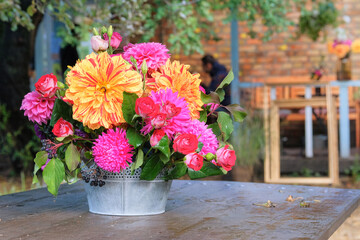 Roses, asters, dahilia in vase in the garden on a wooden table. Sunny day. Bright rural design.