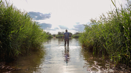 A fisherman using a fishing rod to catch carp in the river while standing in the water. A fisherman...