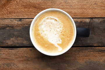 White cup with coffee on a wooden table.