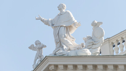 Front view of Saint Karl Cathedral main gate sculptures with a praying priest and angels in Vienna,...
