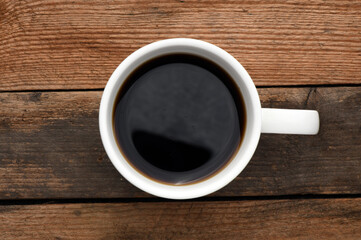 White cup with coffee on a wooden table.