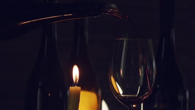 close up of decanting a glass of red wine from a decanter against a background and burning candles