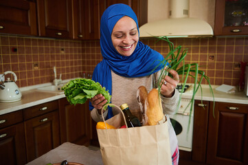 Beautiful Middle-Eastern Muslim woman in blue hijab, arrives home after shopping for groceries....