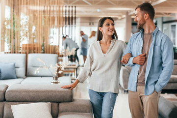 Fototapeta premium Walking around. Couple choosing the sofa and bed in the store