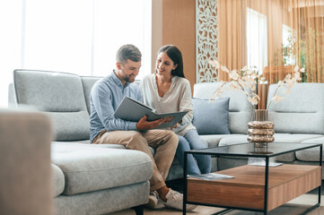 Sitting and reading the catalogue. Couple choosing the sofa and bed in the store