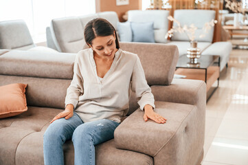 Obraz premium Sitting and relaxing. Woman is visiting bed store. Looking for comfortable sofa