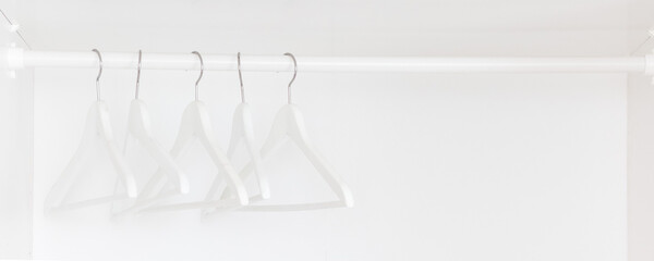 White hangers in a white wardrobe. Minimalism. Texture. Backgroung
