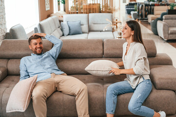 Happy couple choosing the sofa and bed in the store