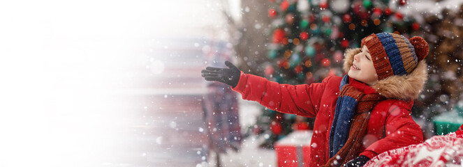 Child in red winter outerwear outdoors in snow showing hand right. New Year Christmas holiday. New...