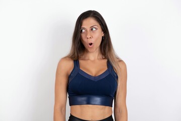 Shocked young beautiful woman wearing sportswear over white background look empty space with open mouth screaming: Oh My God! I can't believe this.