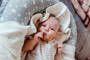 Newborn kid on white plaid. Infant baby in cocoon.