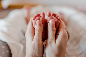 Newborn kid's feet. Mother holds baby's feet.