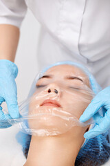 Fototapeta premium beautician applies the mask to the face of beautiful woman