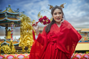 Fototapeta na wymiar carnival country. portrait of a woman. person in traditional costume. woman in traditional costume. Beautiful young woman in a bright red dress and a crown of Chinese Queen posing against the ancient 