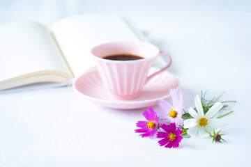 Obraz na płótnie Canvas ピンクのコーヒーカップのコーヒーと見開きの本ととコスモスの花と見開きの白い本（白バック）