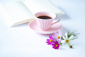 Fototapeta na wymiar ピンクのコーヒーカップのコーヒーと見開きの本ととコスモスの花と見開きの白い本（白バック）