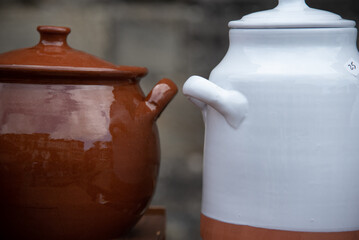 Plano detalle de dos vasijas de barro cocido una marrón y la otra de color blanco expuestas en el...