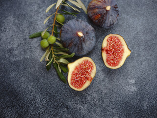 fresh ripe figs fruit and olive branch on dark table. mediterranean food concept