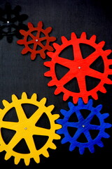 Colorful wooden gears on a black background. Space for text. A toy for children's development