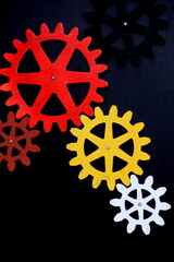 Colorful wooden gears on a black background. Space for text. A toy for children's development