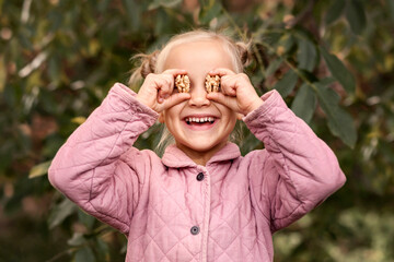 Walnut Nut are tasty and healthy for Сhildren. Walnuts in Child Hands in Walnuts Tree Background
