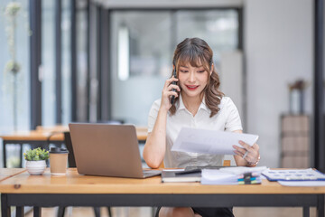 Beautiful Young business Asian Woman Talking on Smartphone in workplace