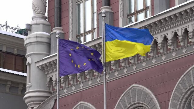 KYIV, UKRAINE - DECEMBER 10, 202: The European Union flag and the Ukrainian flag are waving on the flagpole near the National Bank of Ukraine.