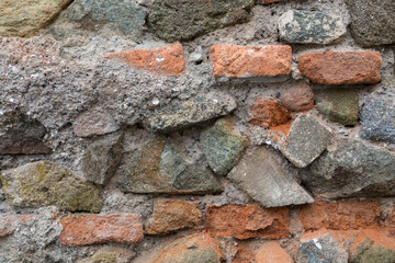 Close up detail of red bricks and stones on an old stone wall. Rough, uneven, urban, grungy texture for backgrounds. Graphic design element.