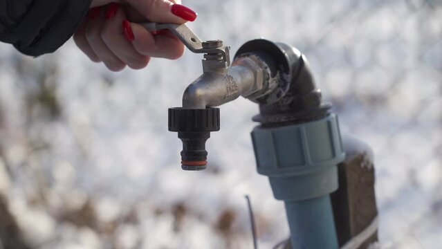 TERNOPIL, UKRAINE - DECEMBER 15, 2021: A woman's hand opens a tap without water. Drought in the countryside. Winter period.
