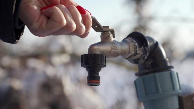 TERNOPIL, UKRAINE - DECEMBER 15, 2021: A woman's hand opens a tap without water. Drought in the countryside. Winter period.
