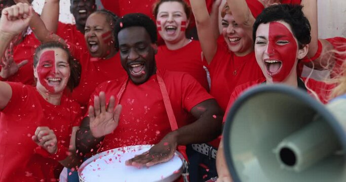 Multiracial red sport fans screaming while supporting their team - Football supporters having fun at competion event - World cup conceptconcept
