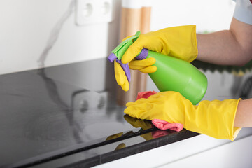Close up shot of female hands holding bottle spray and rag for cleaning the stove	