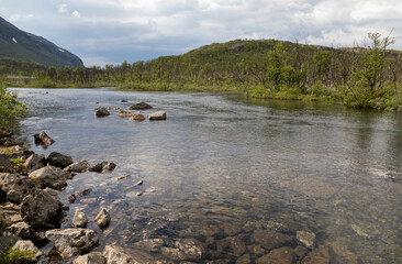 Mountain river under a cloudy sky on a summer day