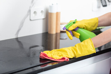 Close up shot of female hands holding bottle spray and rag for cleaning the stove	