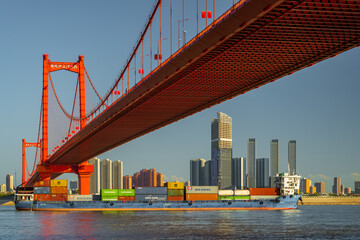 A cargo ship full of containers is passing through the Yingwuzhou great bridge in Wuhan, Hubei,...