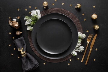 New Year black table setting with elegant golden decorations on black table for festive dinner and...