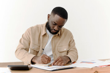 Serious african american man reading notes in business paperwork while sitting at home and working on economic project