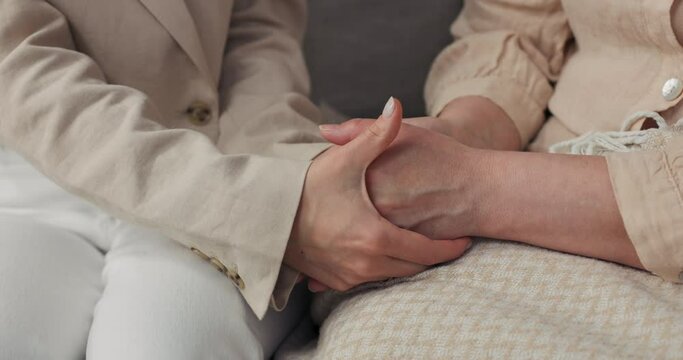 Care, support concept - close-up of an older woman and a young woman holding hands.