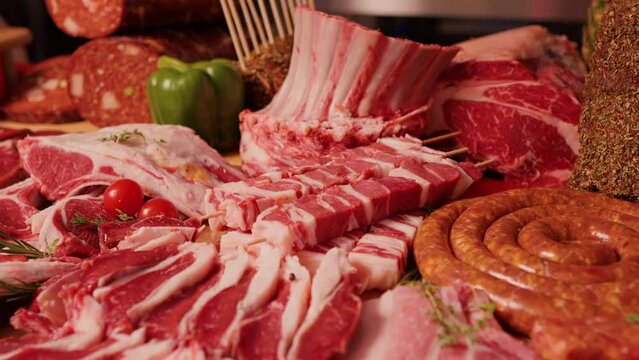 Various sausages and raw meat chunks. Large range of meat goods layed in a decorative way.