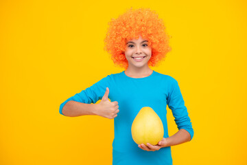 Funny teenage girl hold citrus fruit pummelo or pomelo, big grapefruit isolated on yellow...