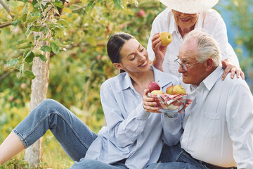 Sitting on the ground. Daughter is with her senior mother and father is in the garden