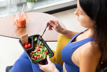 Fit woman eating healthy food at home.