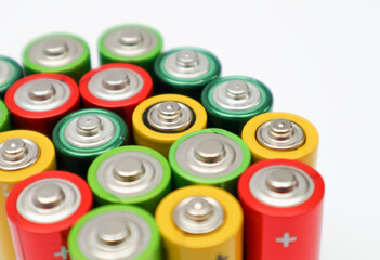 Different colours of batteries on white background. Close up of positive ends batteries, selective...