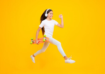 Teen girl 12, 13, 14 years old with skateboard over studio background. Jump and run. Cool modern teenager in stylish clothes. Teenagers lifestyle, casual youth culture. Happy teenager portrait.
